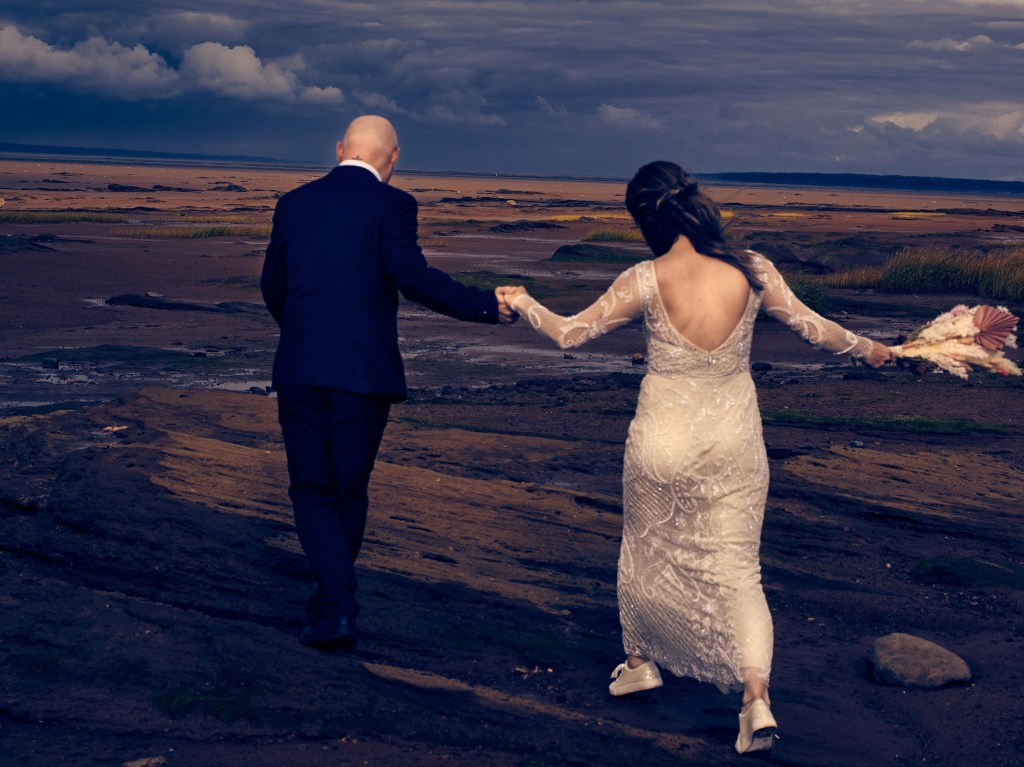 Bride and groom walking together on a beach