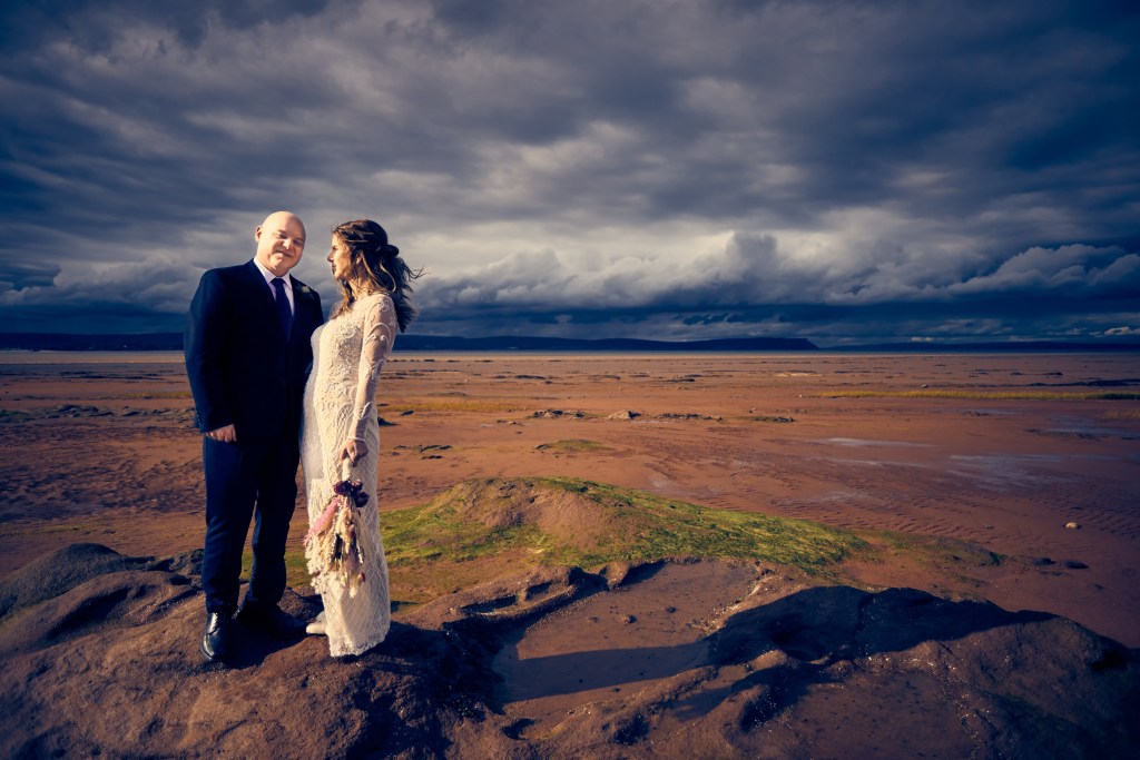 Bride and groom embracing on a rocky coastline